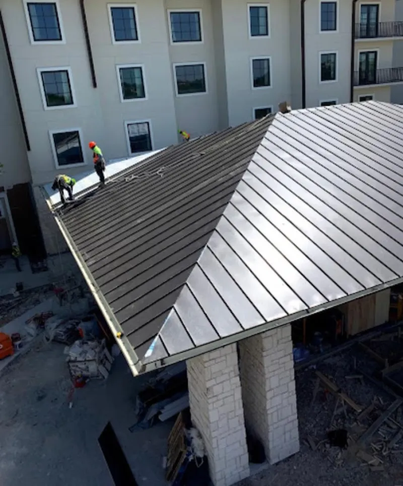 Crew installing standing seam metal roof panels on a commercial project in West Clarkston-Highland